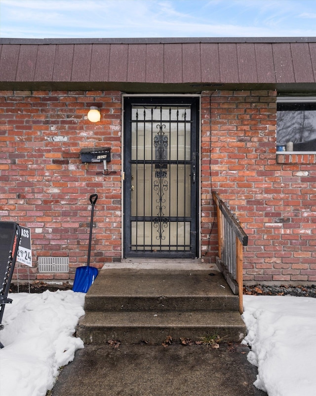 property entrance with visible vents and brick siding