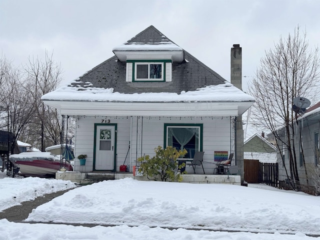 bungalow-style house with a porch, fence, and a chimney