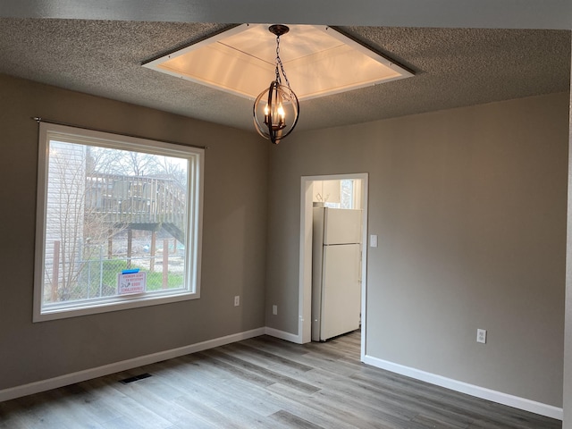 spare room featuring a textured ceiling, wood finished floors, and baseboards