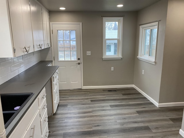 doorway with a sink, recessed lighting, dark wood finished floors, and baseboards