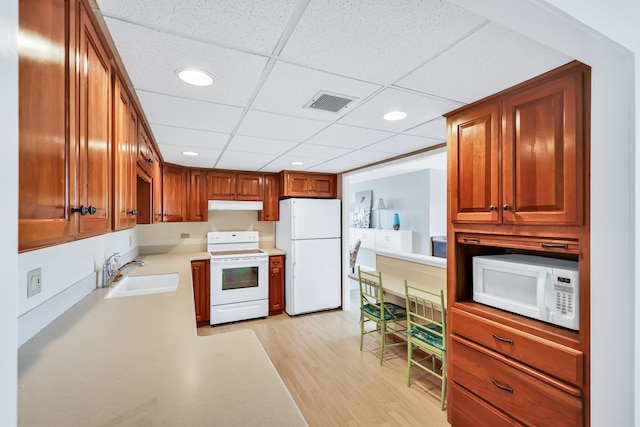 kitchen featuring light countertops, visible vents, light wood-style floors, a sink, and white appliances