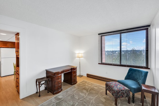 living area with a baseboard radiator, light wood-style flooring, baseboards, and a textured ceiling