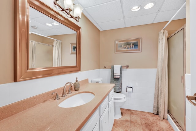 bathroom featuring a paneled ceiling, a stall shower, toilet, and vanity