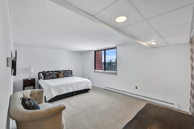 carpeted bedroom with a paneled ceiling, a baseboard radiator, and baseboards