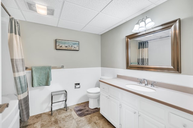 full bathroom featuring a drop ceiling, toilet, a wainscoted wall, visible vents, and vanity