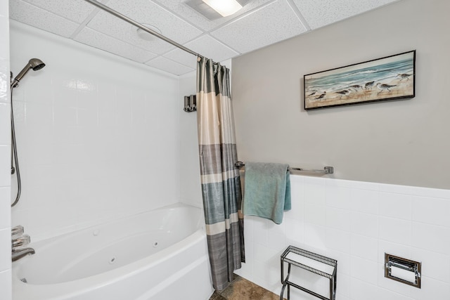 bathroom featuring tile walls, a paneled ceiling, and shower / tub combo with curtain