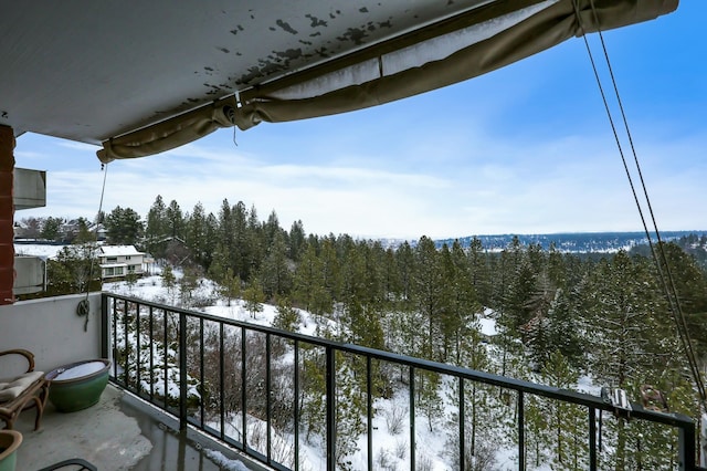 snow covered back of property featuring a view of trees