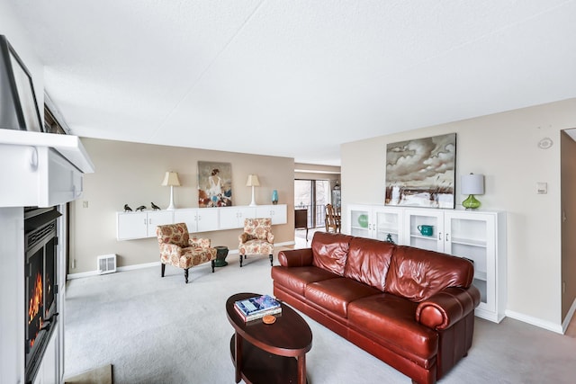 living area with carpet floors, a warm lit fireplace, and baseboards