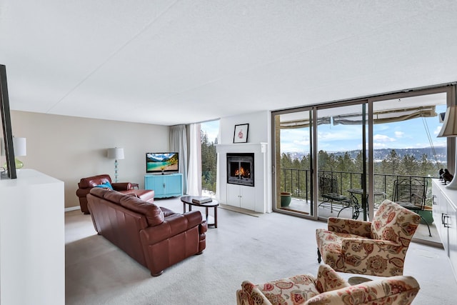 living room featuring a warm lit fireplace, light colored carpet, and floor to ceiling windows