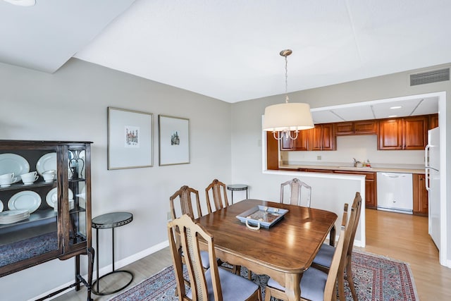 dining room featuring light wood-type flooring, visible vents, and baseboards