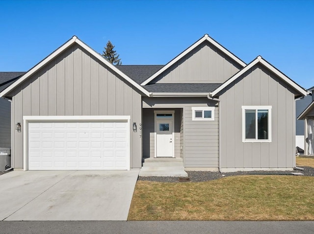 view of front of property featuring an attached garage, a front lawn, concrete driveway, and roof with shingles