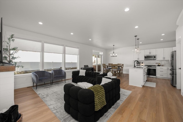 living room with light wood-type flooring, an inviting chandelier, and recessed lighting