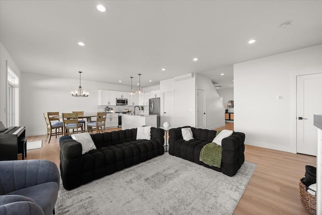 living room with light wood-type flooring, baseboards, a notable chandelier, and recessed lighting