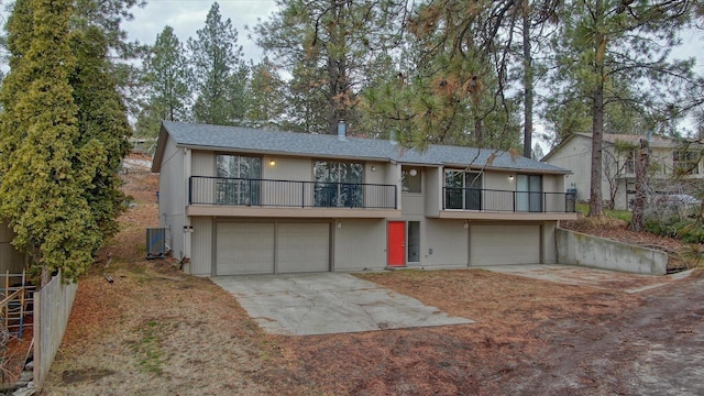 view of front facade with a garage, driveway, a balcony, and central AC unit