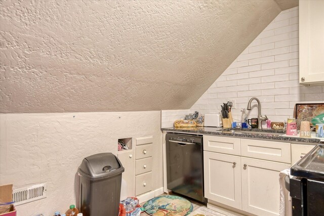 kitchen featuring lofted ceiling, a textured wall, a sink, dishwasher, and tasteful backsplash