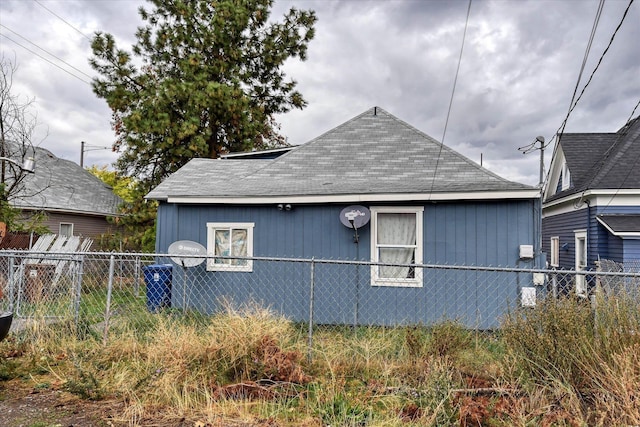 view of side of home with a shingled roof and fence