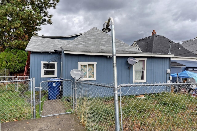 view of home's exterior with a yard, a shingled roof, fence private yard, and a gate