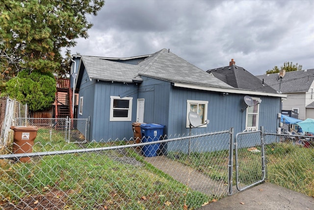 view of side of property featuring a fenced front yard, a chimney, a gate, and stairway