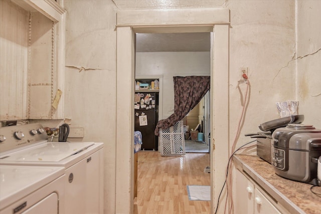 laundry area with light wood-style flooring, independent washer and dryer, and cabinet space