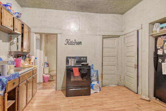 kitchen with black range with electric stovetop, a sink, brown cabinets, open shelves, and light wood finished floors