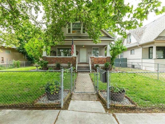 view of front of property featuring a fenced front yard, covered porch, a gate, a front yard, and brick siding