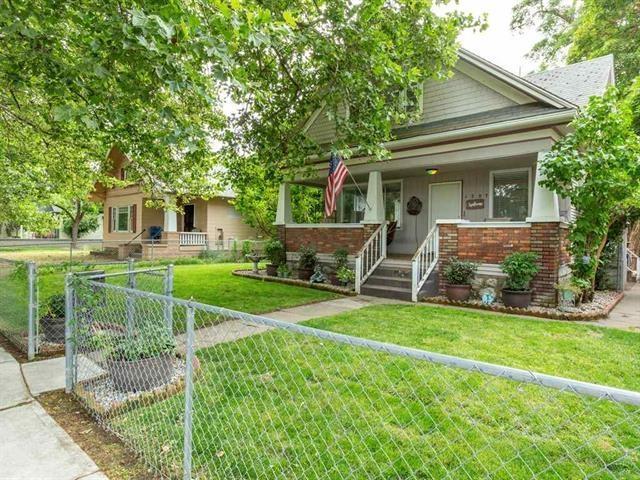 view of front of property featuring covered porch, a front yard, fence, and brick siding