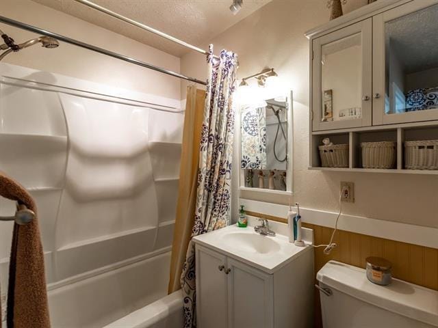 full bath with shower / bath combo, a wainscoted wall, vanity, and toilet