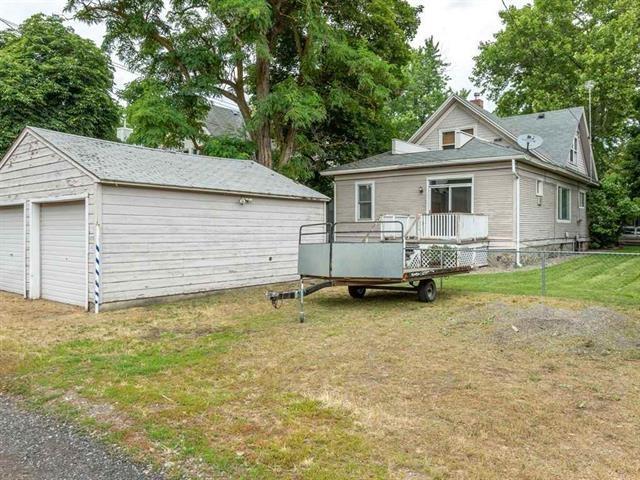 view of front of home featuring a detached garage, fence, a deck, an outdoor structure, and a front yard