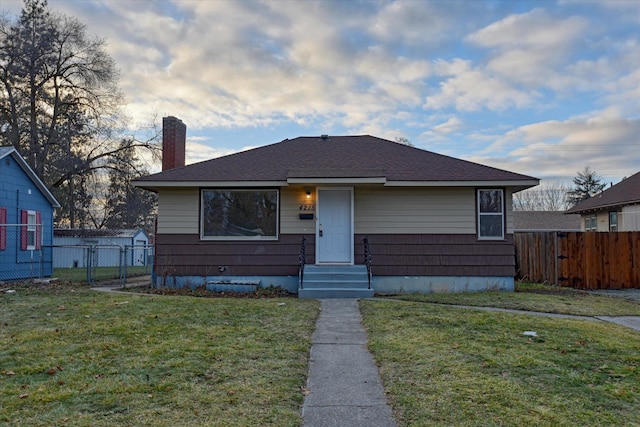 bungalow-style home with a front yard, fence, and a chimney