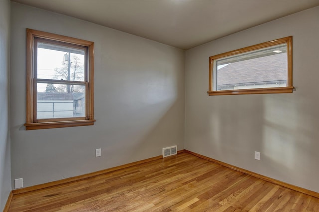 unfurnished room with light wood-style flooring, visible vents, and baseboards