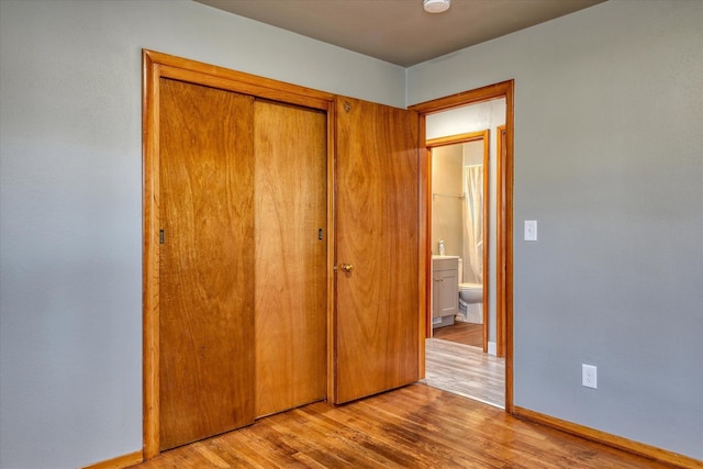 unfurnished bedroom featuring a closet, wood finished floors, and baseboards