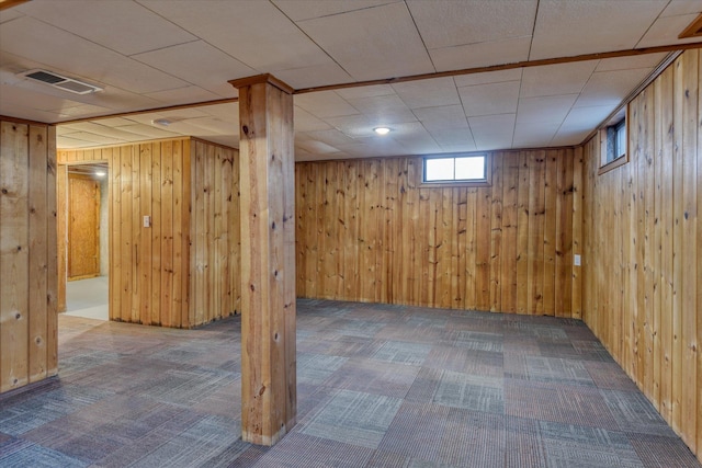 below grade area featuring wood walls, carpet, and visible vents