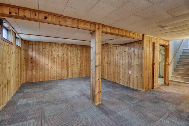 basement with wood walls, stairway, and carpet flooring