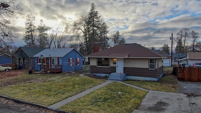 bungalow with a deck, a front yard, and fence