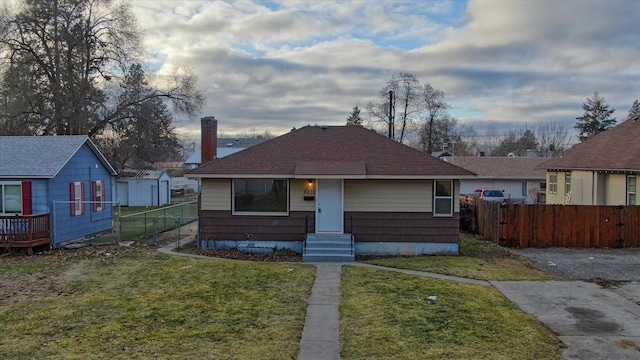 bungalow-style home with a front yard, fence, and entry steps