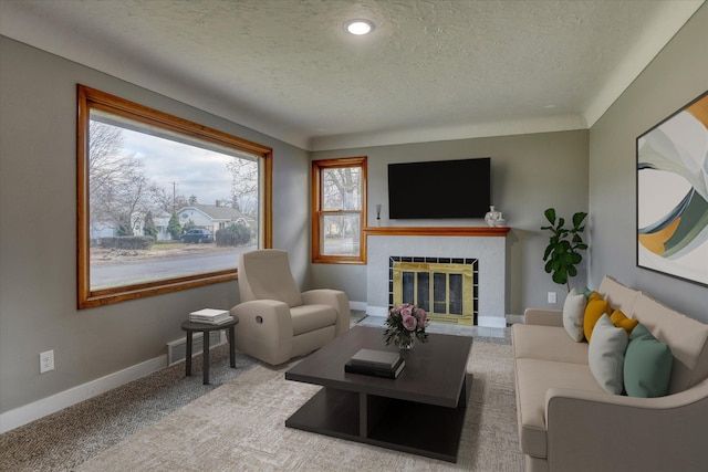 living room featuring a tile fireplace, carpet flooring, a textured ceiling, and baseboards