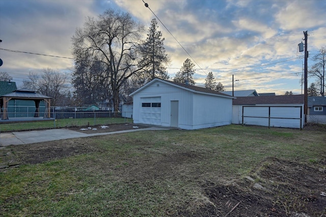 exterior space with a garage, driveway, an outbuilding, fence, and a gazebo