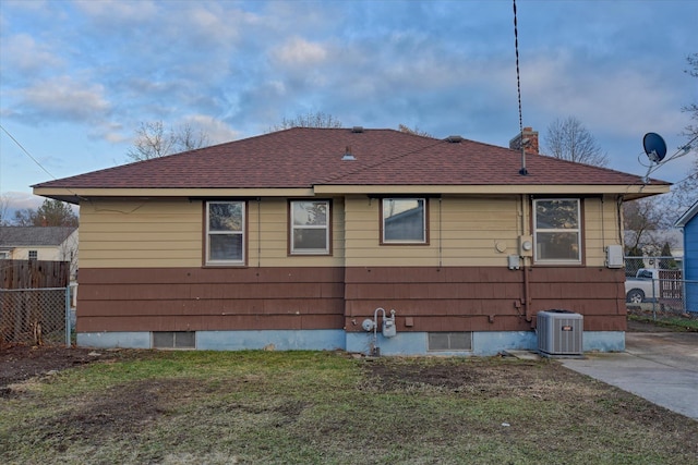 exterior space with roof with shingles, a lawn, fence, and central air condition unit