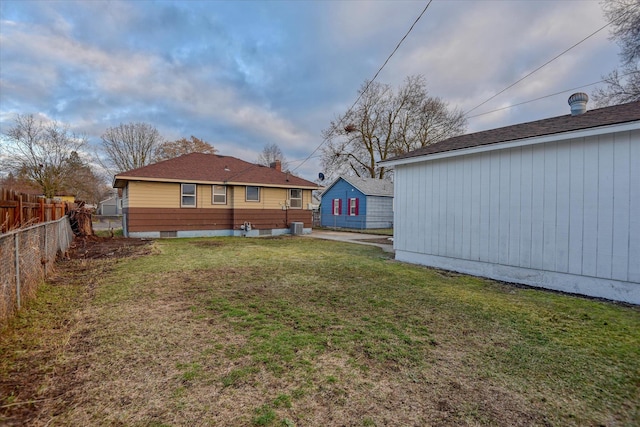 rear view of house featuring a yard, cooling unit, and fence