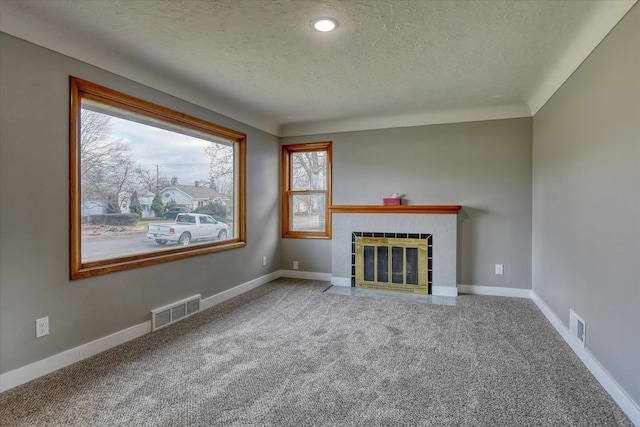 unfurnished living room featuring a tile fireplace, baseboards, visible vents, and carpet flooring