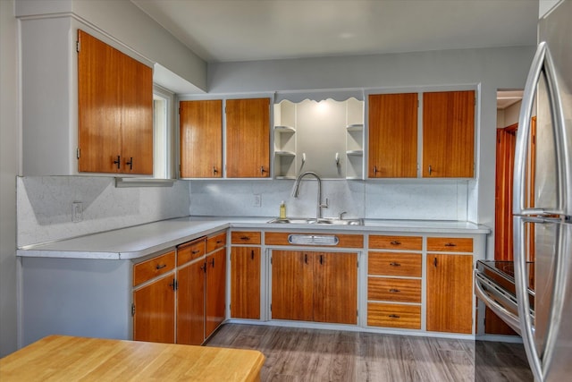 kitchen with appliances with stainless steel finishes, brown cabinets, light countertops, open shelves, and a sink