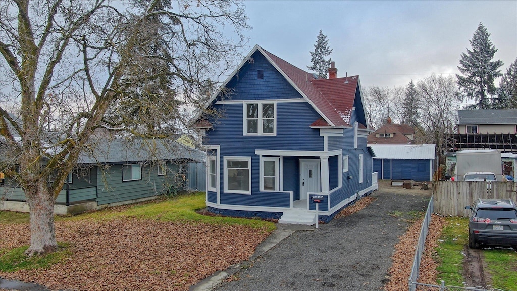 view of front of house featuring a porch, driveway, and a chimney