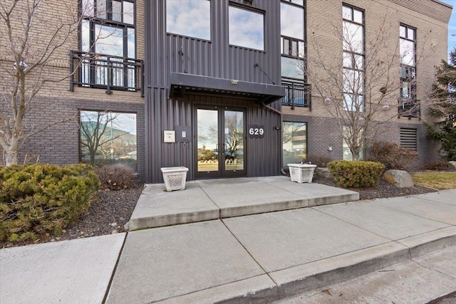 property entrance featuring brick siding, board and batten siding, and a balcony