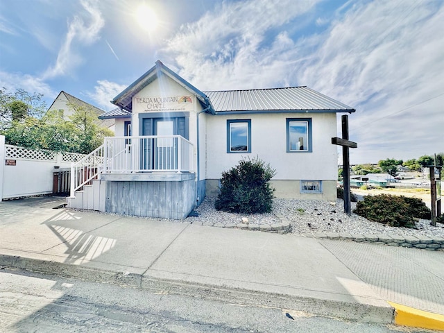 view of front of house with fence, metal roof, and stucco siding