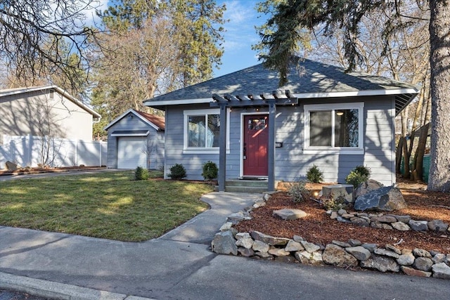 view of front of property with a detached garage, a shingled roof, fence, an outdoor structure, and a front lawn