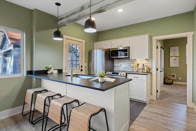 kitchen with dark countertops, appliances with stainless steel finishes, a breakfast bar, and a sink