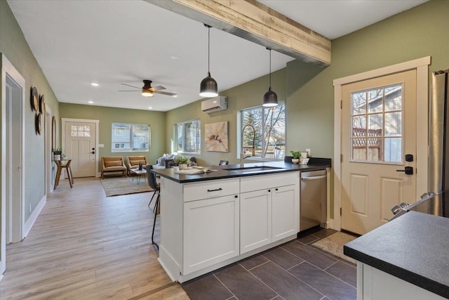 kitchen featuring dark countertops, an AC wall unit, a sink, dishwasher, and a peninsula