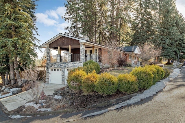 view of front of home featuring a garage, stone siding, driveway, and a balcony