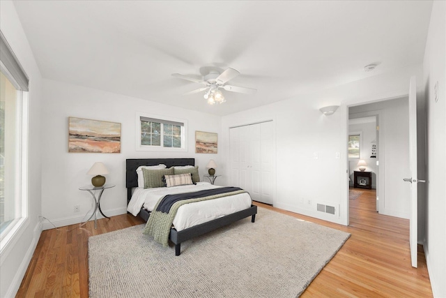 bedroom with baseboards, visible vents, ceiling fan, light wood-style floors, and a closet