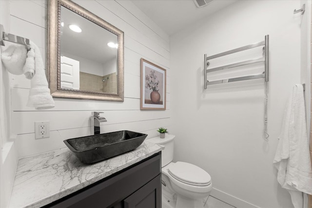 bathroom with wood walls, vanity, toilet, and baseboards